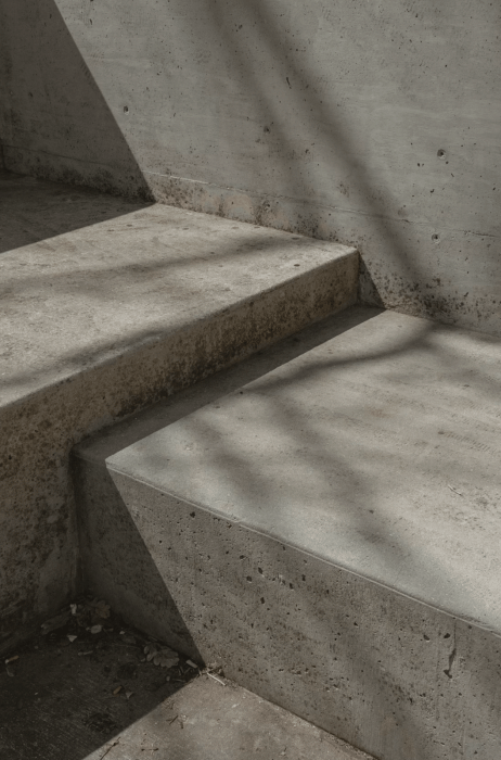 Concrete calculator interface displaying input fields for length, width, thickness with unit selectors (feet, metres, inches) and instant calculation results showing cubic yards, bag quantities needed, total weight and estimated UK cost for slabs, columns, stairs and footings